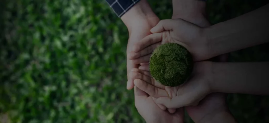 A set of hands on a green backdrop representing sustainability.